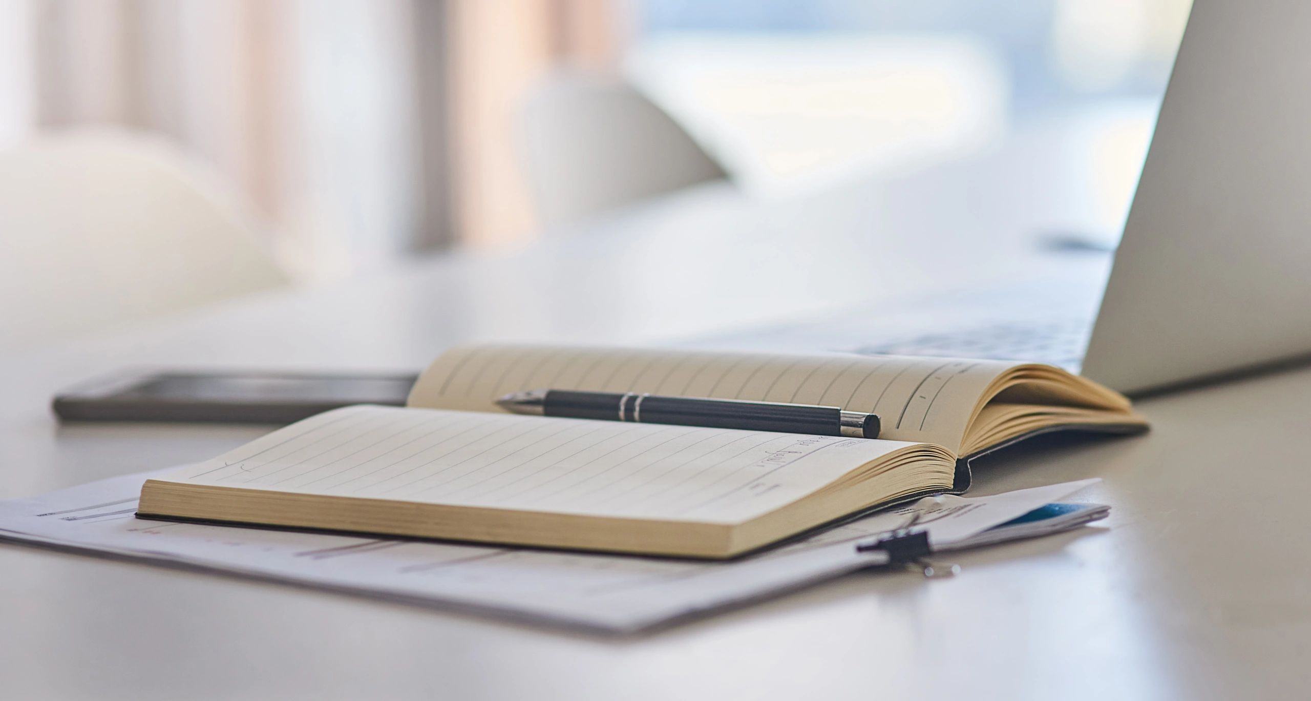 Notebook and laptop on a desk for reflective coaching work.